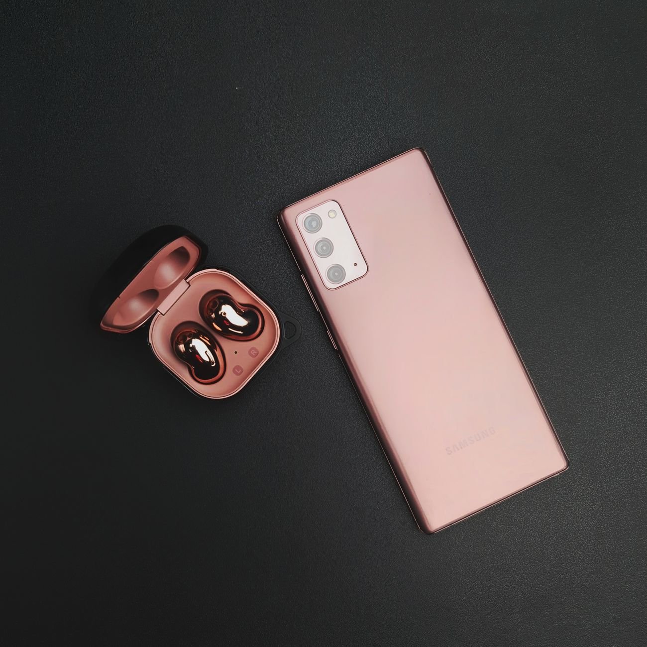 A modern smartphone paired with wireless earbuds on a minimalist black background.